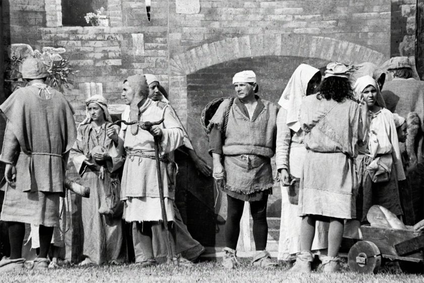 A group of men and women dressed in medieval garb are looking tiredly ahead