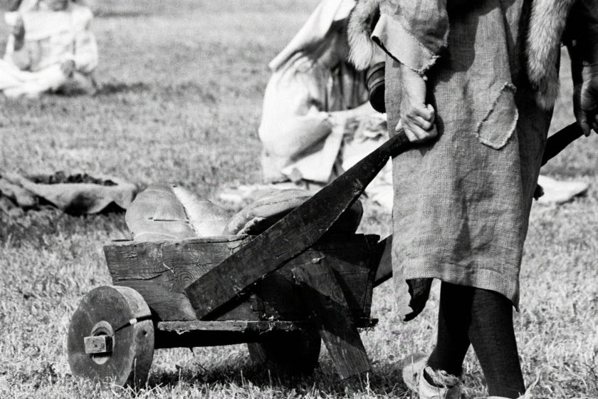 A woman in medieval gars is wheeling a cartwheel